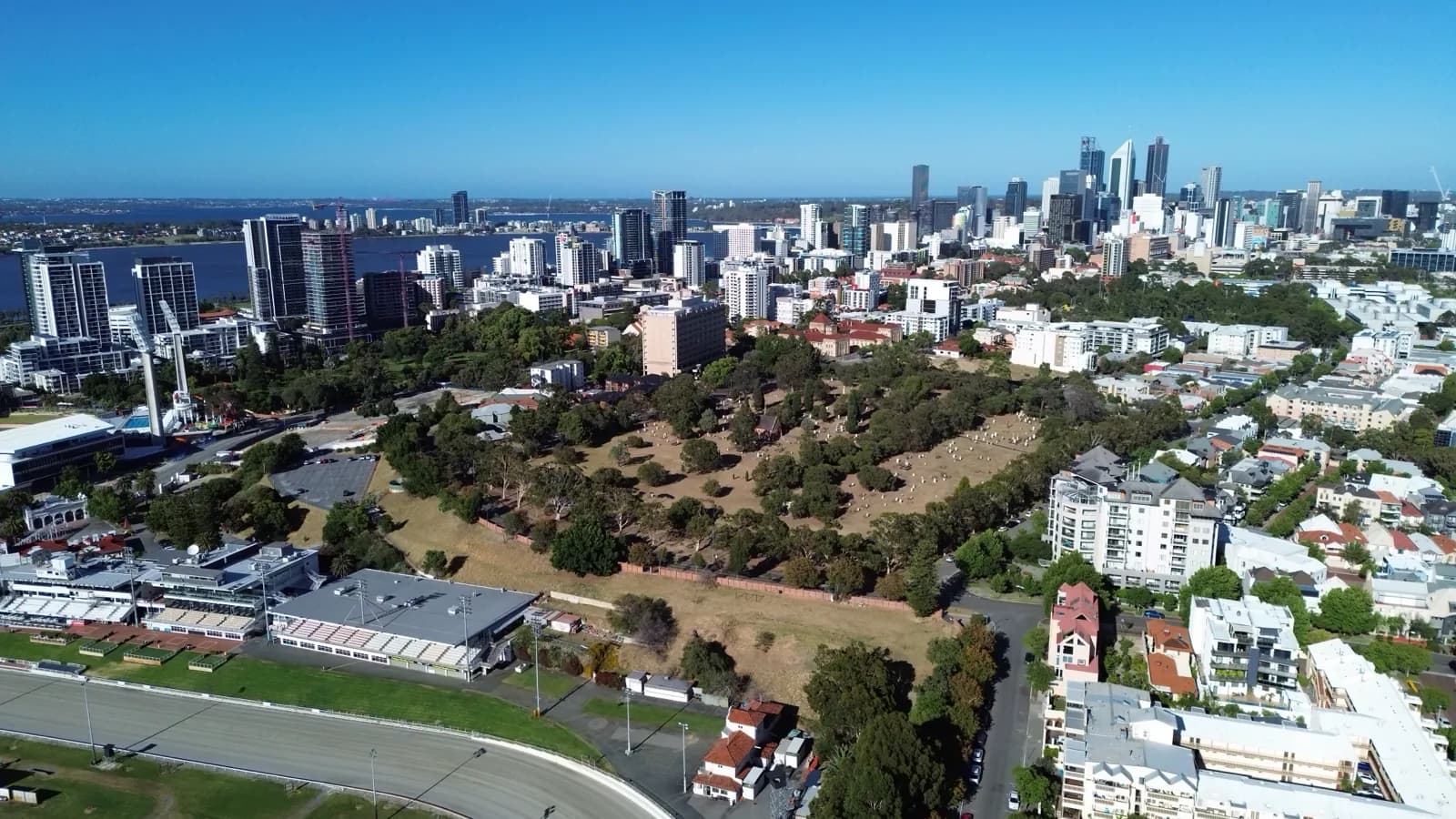 Aerial photograph of Perth, looking across parkland and residential streets towards the city skyline.