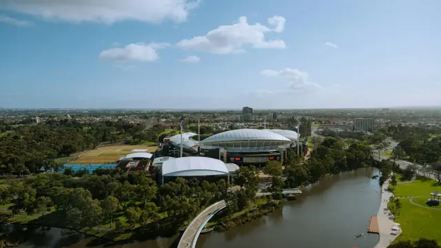 Aerial photograph of Adelaide Oval beside the River Torrens, with the parklands, North Adelaide and the suburbs beyond.
