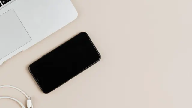 Laptop, smartphone and charging cable on a desk; contextual photo, not a compared charger.